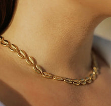Load image into Gallery viewer, Close-up image of a gold seashell chain necklace on a person's neck, showcasing the chain design and shine.