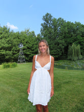Load image into Gallery viewer, Woman in a white dress standing in a grassy field with trees and a windmill in the background.