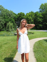 Load image into Gallery viewer, Woman in a white dress standing in a park with trees and grass.
