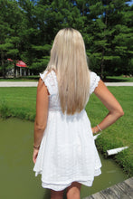 Load image into Gallery viewer, Woman in a white dress standing by a pond with trees in the background