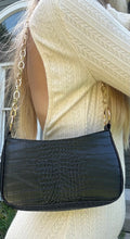 Load image into Gallery viewer, A black snakeskin mini handbag with an adjustable shoulder strap being modeled.