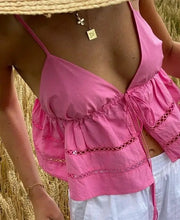 Load image into Gallery viewer, This image features a vibrant pink, tie-front halter crop top, perfect for summer. The halter neckline ensures a cool and comfortable fit, while the adjustable tie-front allows for a customizable silhouette that flatters the figure.