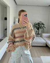 Load image into Gallery viewer, A woman takes a mirror selfie in a bright, modern living room, wearing a beige knit sweater with horizontal stripes in black, rust orange, and red, paired with light gray cargo pants.
