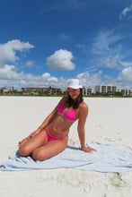 Load image into Gallery viewer, Woman in a pink bikini on a beach with a blue sky and white clouds.
