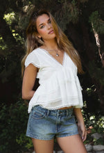 Load image into Gallery viewer, Woman wearing a white blouse and denim shorts standing in a forest setting