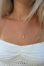 Load image into Gallery viewer, A close-up of a model wearing a delicate gold necklace with a small textured seahorse pendant, paired with a white ribbed knit top.