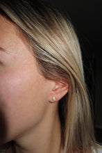 Load image into Gallery viewer, Close-up of a person wearing a gold earring with a dark background