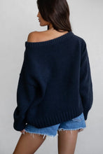 Load image into Gallery viewer, A woman shown from the back wearing an oversized off-the-shoulder knit sweater in dark navy blue, paired with light blue denim shorts against a plain light gray background.