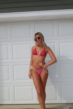 Load image into Gallery viewer, Person wearing a red bikini standing against a white paneled wall.