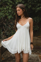 Load image into Gallery viewer, Woman in a white dress standing outdoors with greenery in the background