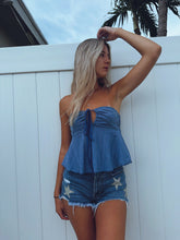 Load image into Gallery viewer, A woman wearing a strapless crop top and denim shorts standing in front of a white fence.