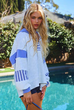 Load image into Gallery viewer, Woman wearing a blue and white sweater by a pool