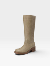 Load image into Gallery viewer, A single knee-high boot in a light taupe-beige color, featuring a low brown block heel and a rounded toe, photographed against a clean white studio background.