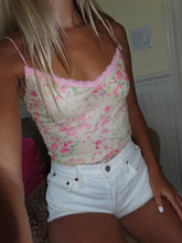 Load image into Gallery viewer, A person wearing a pink and yellow floral lace tank top with thin straps, paired with white shorts.