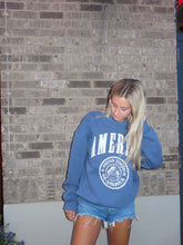 Load image into Gallery viewer, Person wearing a blue hoodie with a logo on a stone floor