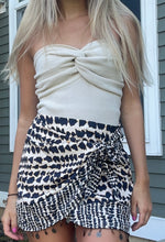 Load image into Gallery viewer, A black and white cheetah print mini tie skirt with a tie-front detail, worn by a model facing away from the camera.