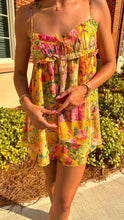 Load image into Gallery viewer, A person wearing a yellow and pink floral mini dress with ruffle detailing and thin straps.