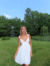 Load image into Gallery viewer, Woman in a white dress standing on grass with trees and a windmill in the background