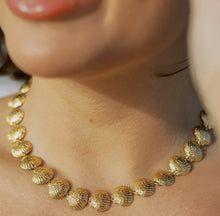 Load image into Gallery viewer, Close-up of a gold seashell choker necklace on a person's neck, showcasing the texture and shine of the gold material.