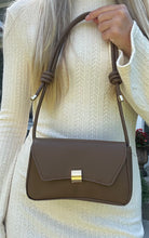 Load image into Gallery viewer, A person wearing a beige sweater holding a brown mini shoulder bag with a metallic buckle.