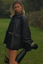 Load image into Gallery viewer, A person wearing a high waisted mini skirt with a black top and black boots, standing outdoors.