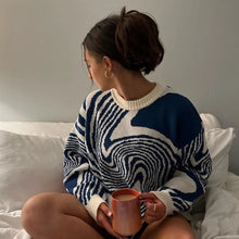 Load image into Gallery viewer, A person sitting on a bed wearing an oversized blue and white sweater, holding a mug.