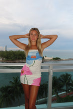Load image into Gallery viewer, Woman in a colorful swimsuit standing by a pool with palm trees in the background