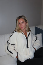 Load image into Gallery viewer, Woman wearing a white Fuzzy Pullover with black trim in a bedroom setting