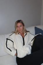 Load image into Gallery viewer, Woman wearing a white coat with black accents in a minimal indoor setting