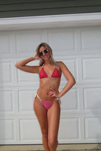 Load image into Gallery viewer, Woman in a red bikini posing against a white paneled wall.
