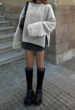 Load image into Gallery viewer, Person wearing a gray sweater, black skirt, and black boots standing on a sidewalk.
