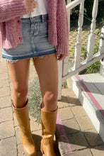 Load image into Gallery viewer, A person wearing a pink knit cardigan, a light blue denim mini skirt, a white top, and tan knee-high boots, standing outdoors on stone steps beside a white railing.
