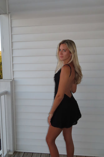 Woman in a black dress standing on a white porch