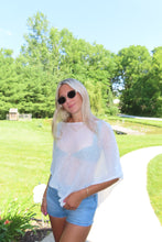 Load image into Gallery viewer, Model wearing a white lightweight knit beach cover-up over a bikini with denim shorts outdoors on a sunny summer day.

