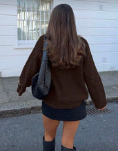 Load image into Gallery viewer, Person wearing a brown jacket and black skirt walking on a sidewalk.
