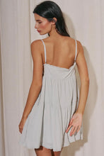 Load image into Gallery viewer, Light sage green babydoll mini dress with adjustable spaghetti straps, lace trim, side tie details, and a flowy tiered skirt for summer.
