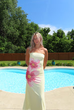 Load image into Gallery viewer, Woman in a floral dress standing by a pool with trees in the background
