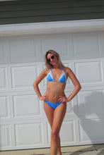 Load image into Gallery viewer, Person wearing a blue bikini standing in front of a white garage door.
