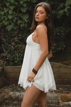 Load image into Gallery viewer, Woman in a white dress standing outdoors with greenery in the background
