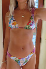 Load image into Gallery viewer, Woman wearing a colorful floral bikini standing indoors.

