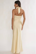 Load image into Gallery viewer, Butter yellow satin halter maxi dress with draped surplice neckline, open tie-back design, and elegant floor-length silhouette for weddings and formal events.
