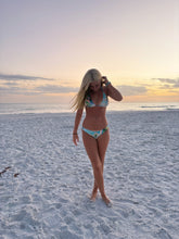 Load image into Gallery viewer, Woman in a bikini standing on a beach at sunset
