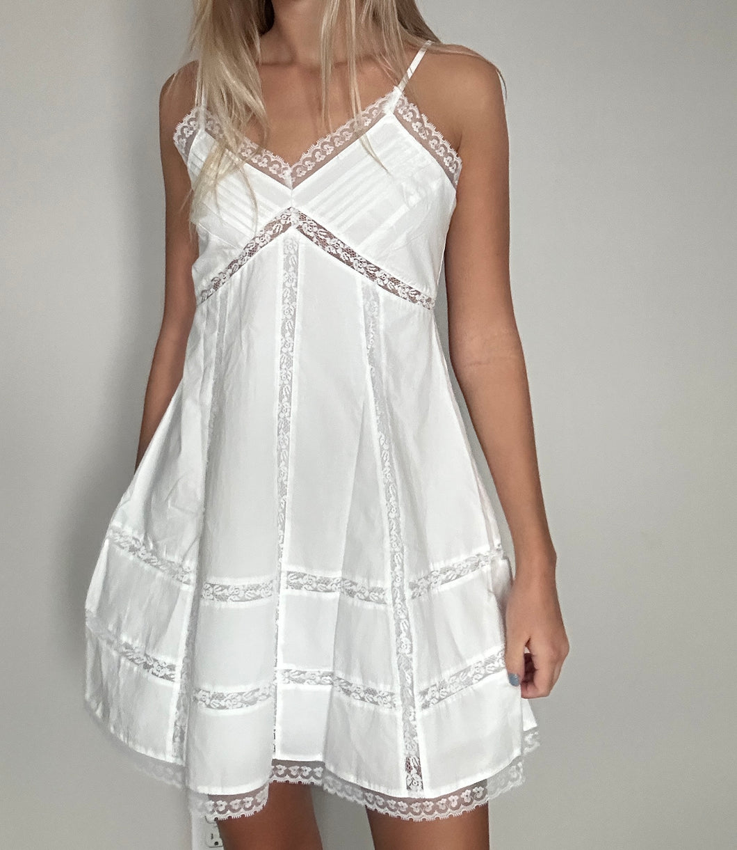 White lace-trimmed dress worn by a person on a plain background