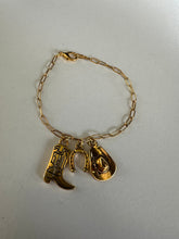 Load image into Gallery viewer, A gold-toned chain bracelet with western-themed charms including a cowboy boot, horseshoe, and star.

