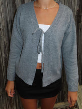Load image into Gallery viewer, Person wearing a gray cardigan over a white top and black shorts against a wooden background
