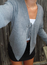 Load image into Gallery viewer, Person wearing a gray cardigan over a white top and black skirt against a wooden fence background
