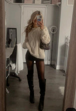 Load image into Gallery viewer, Person wearing a white cable knit sweater, black shorts, and knee-high boots in a room.
