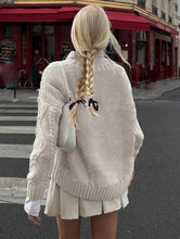 Load image into Gallery viewer, Person wearing a beige sweater and white skirt on a city street.
