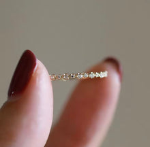 Load image into Gallery viewer, Gold ring with small diamonds held between fingers against a neutral background
