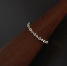 Load image into Gallery viewer, Delicate silver ring with small diamonds on a dark wooden surface
